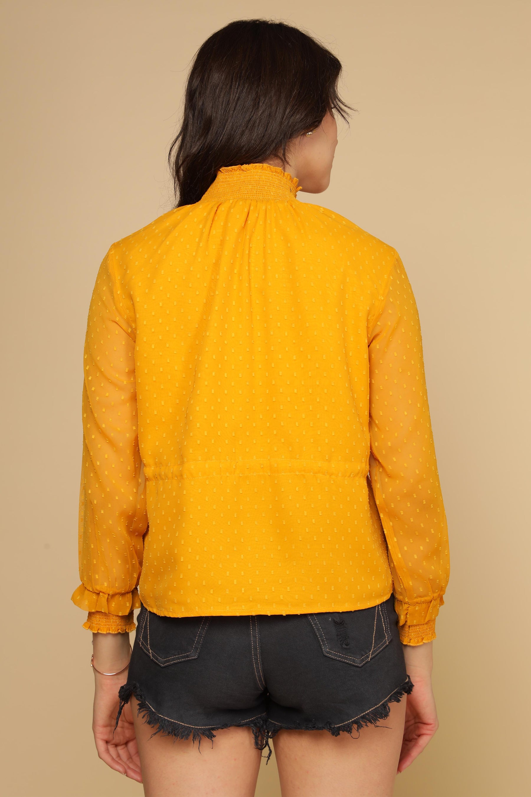 Back view of a vibrant yellow chiffon top with ruffled collar.