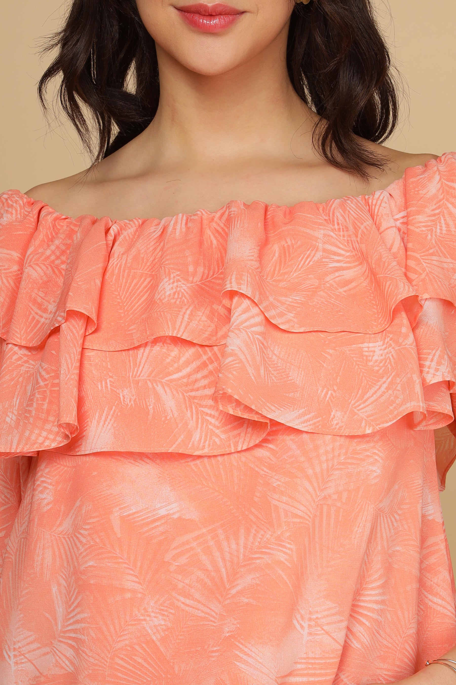 Peach printed top with ruffled neckline and tropical pattern.