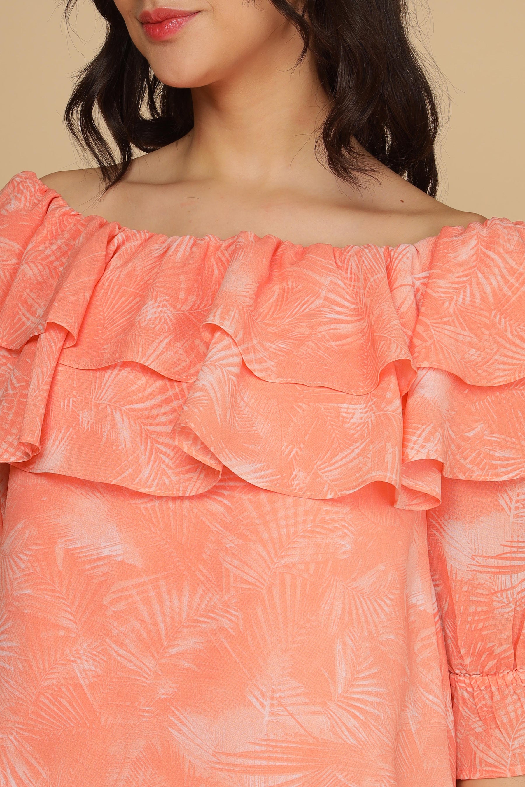 Peach printed top with ruffled neckline and tropical leaf design.