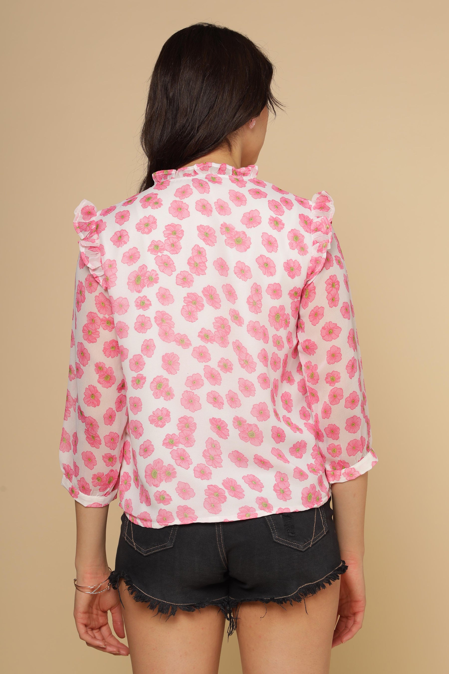 Back view of pink ruffle floral top on model.