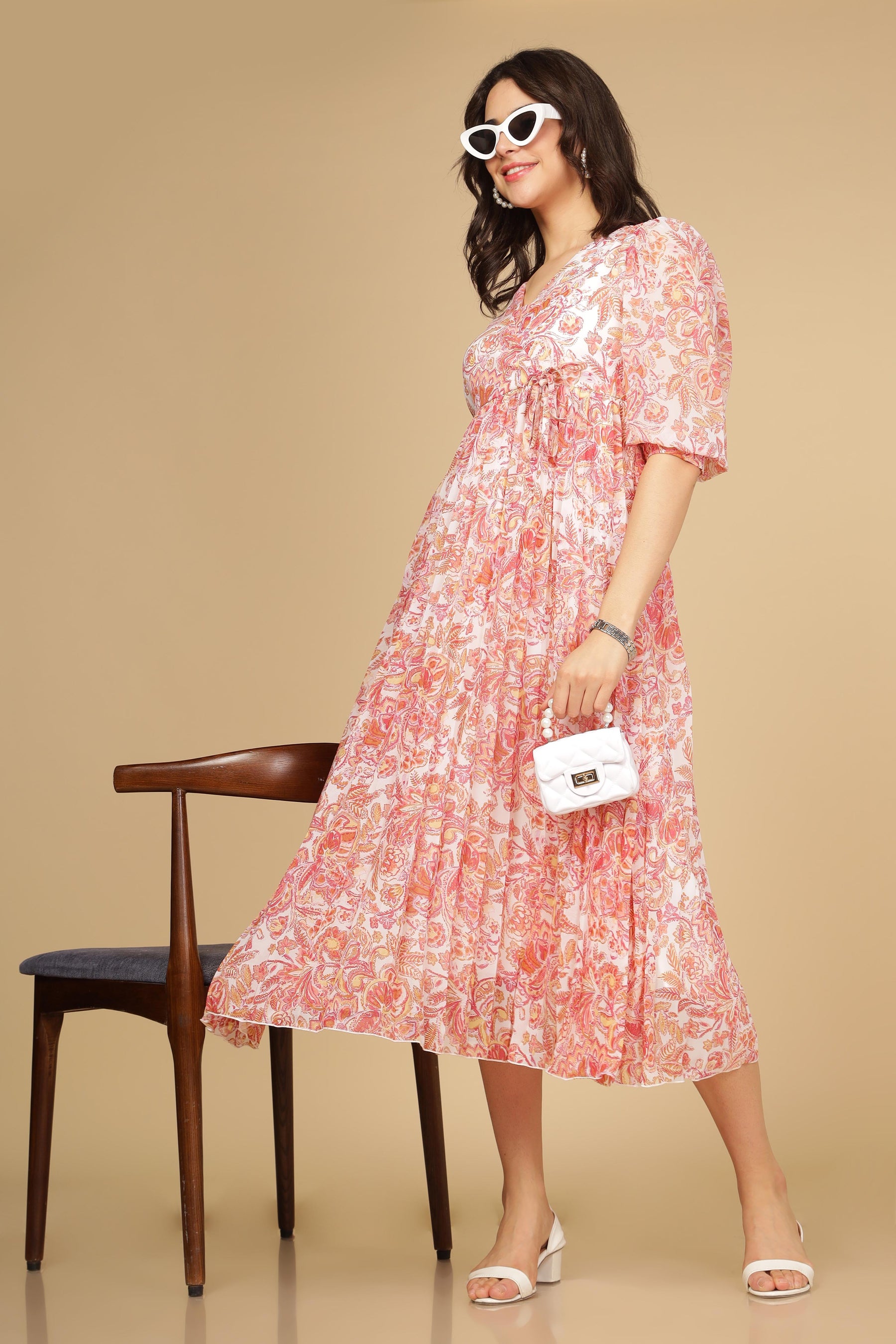 Elegant pleated maxi dress with floral motif and white accessories.