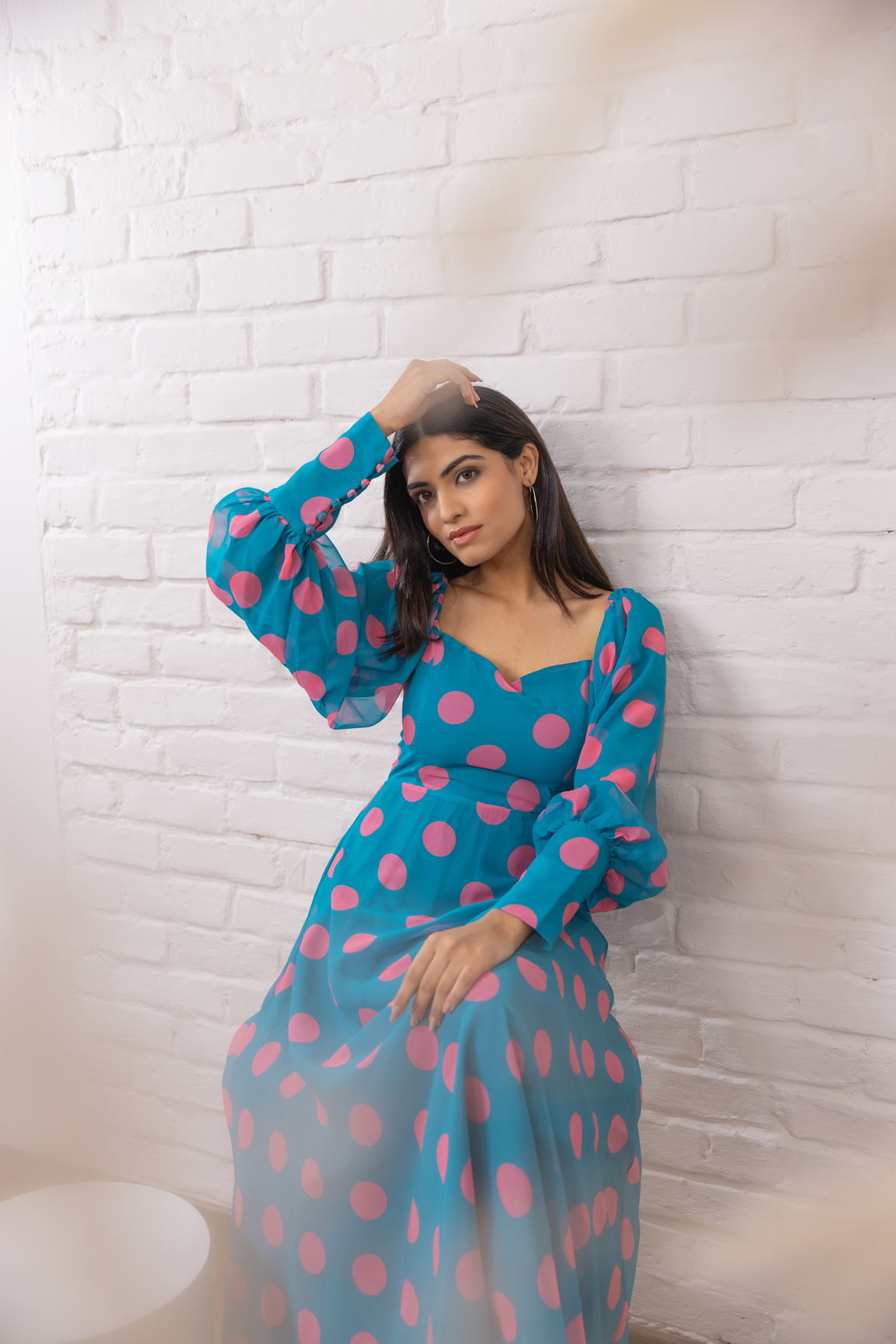 Stylish model wearing a blue polka dot maxi dress against a white backdrop.