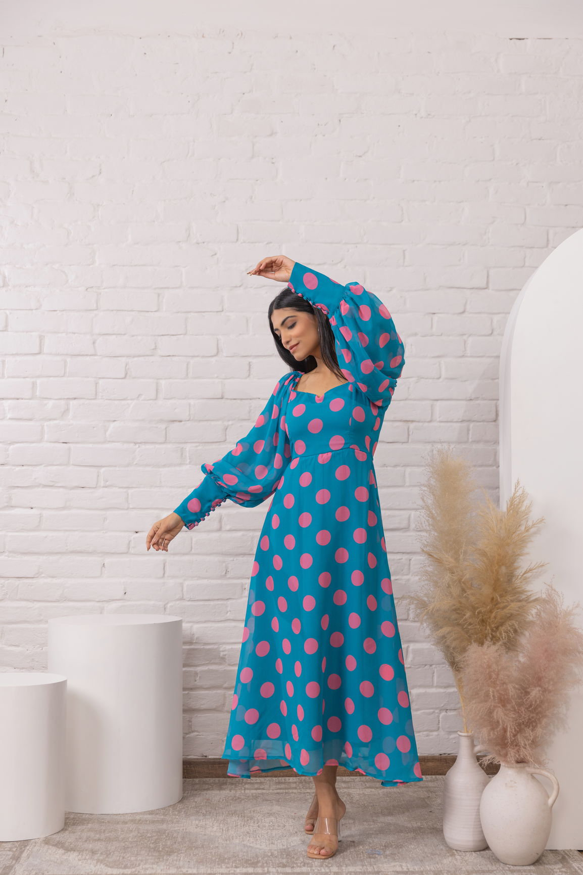 Blue polka dot maxi dress featuring long sleeves and a flowing silhouette.