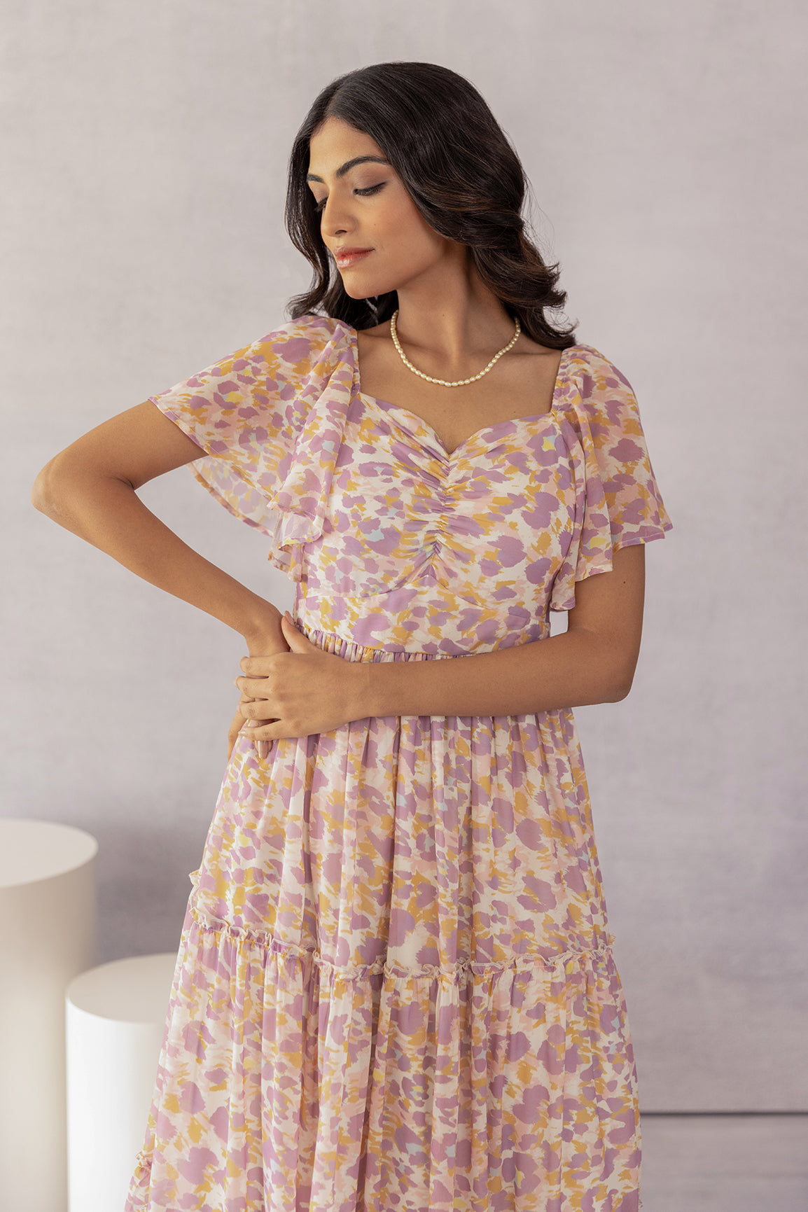 Mosaic print maxi dress with flutter sleeves and pearl necklace.