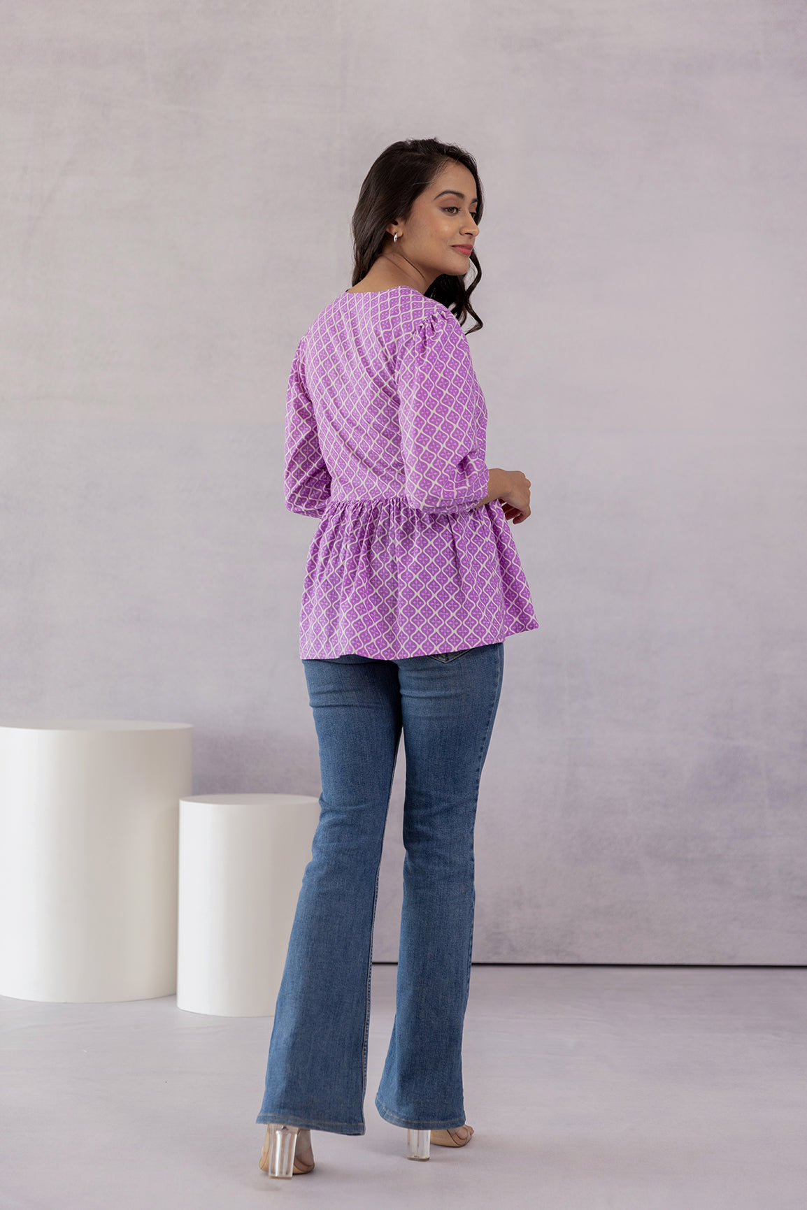 Woman wearing lilac cotton top with flared jeans.