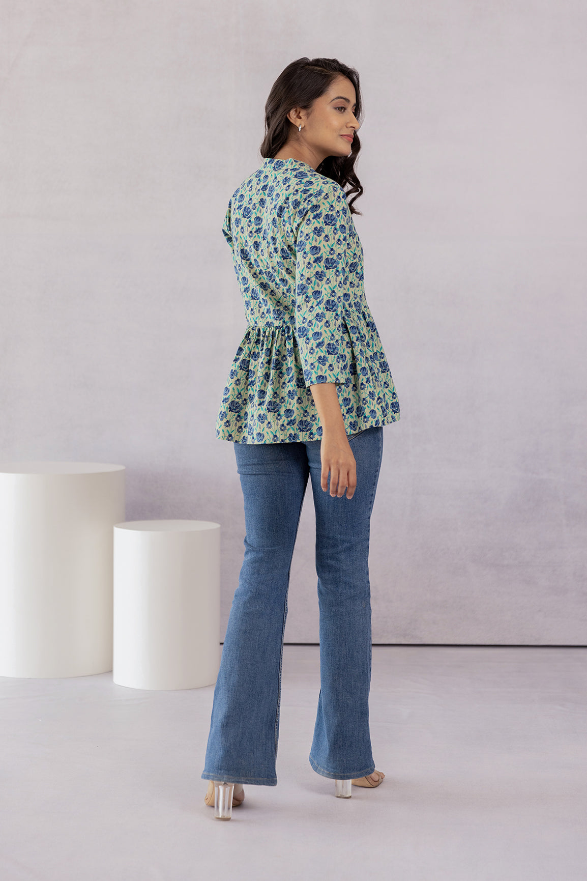 Back view of woman in green cotton floral top and jeans.