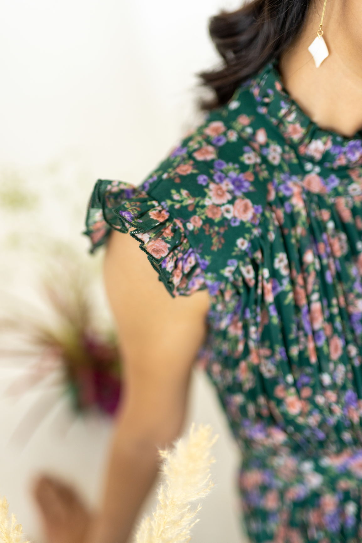 Emerald pleated maxi dress with floral pattern and ruffled sleeves.