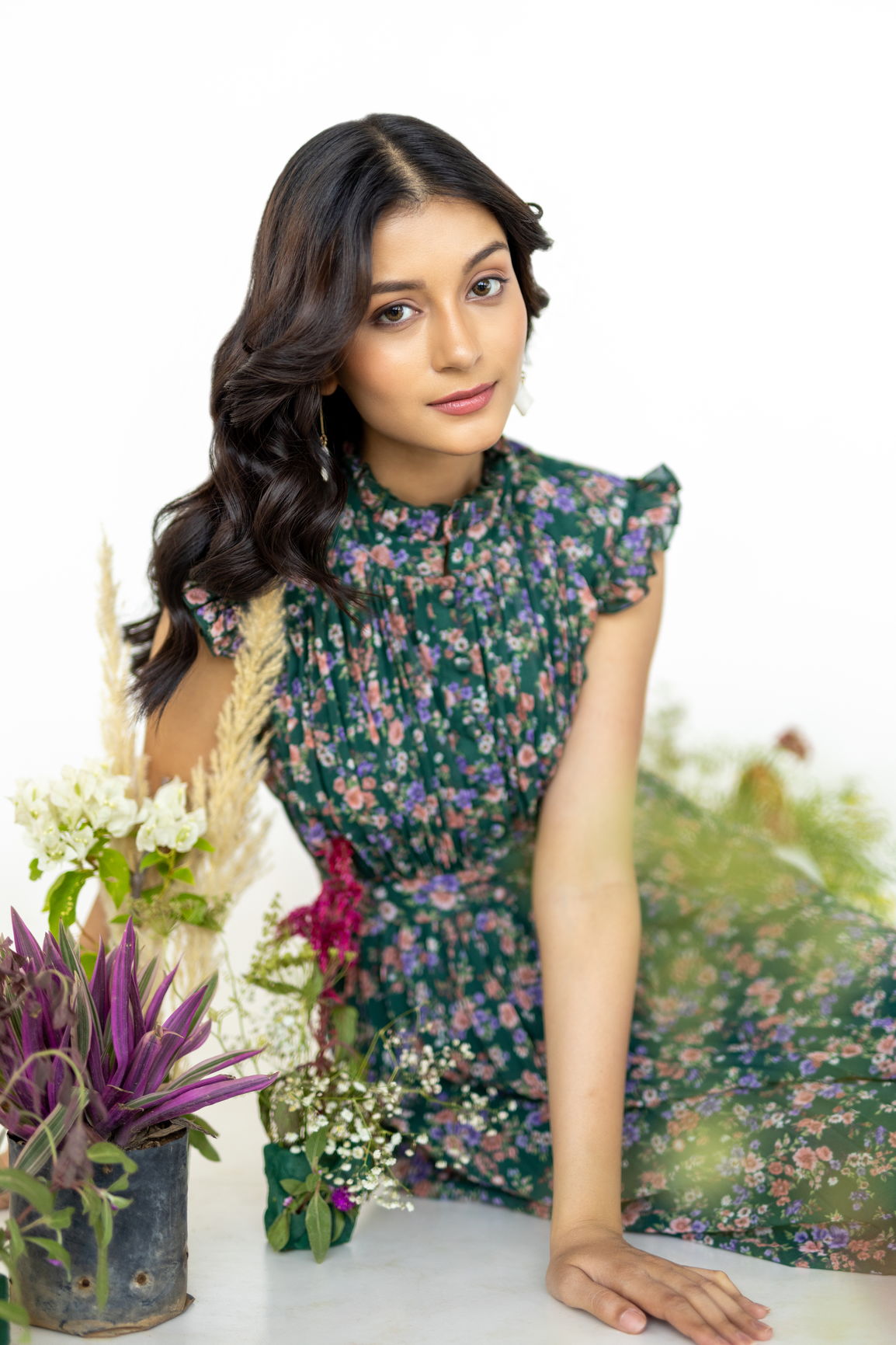 Model in an emerald pleated maxi dress with floral accents.