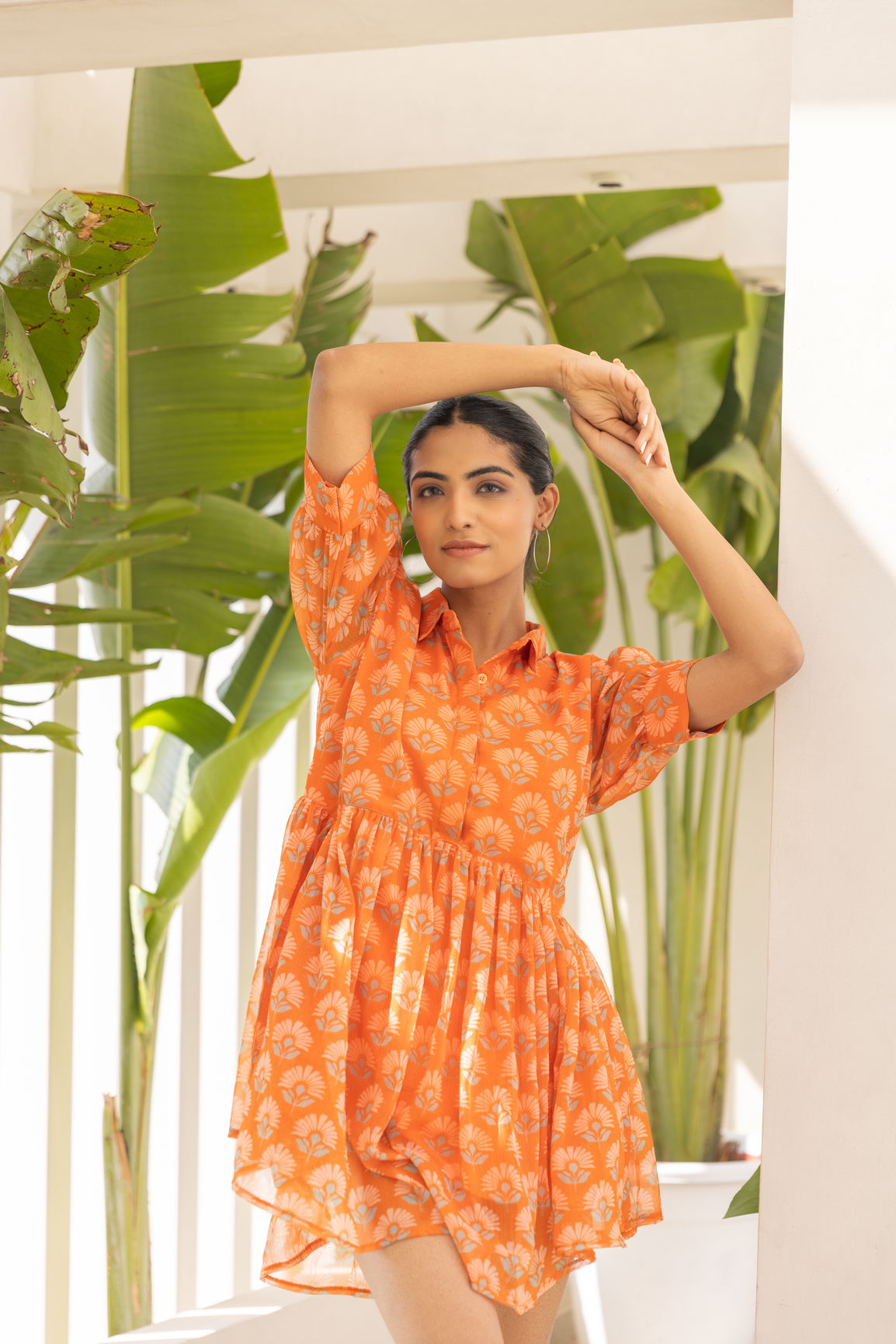 Model wearing orange floral mini dress in a bright setting.