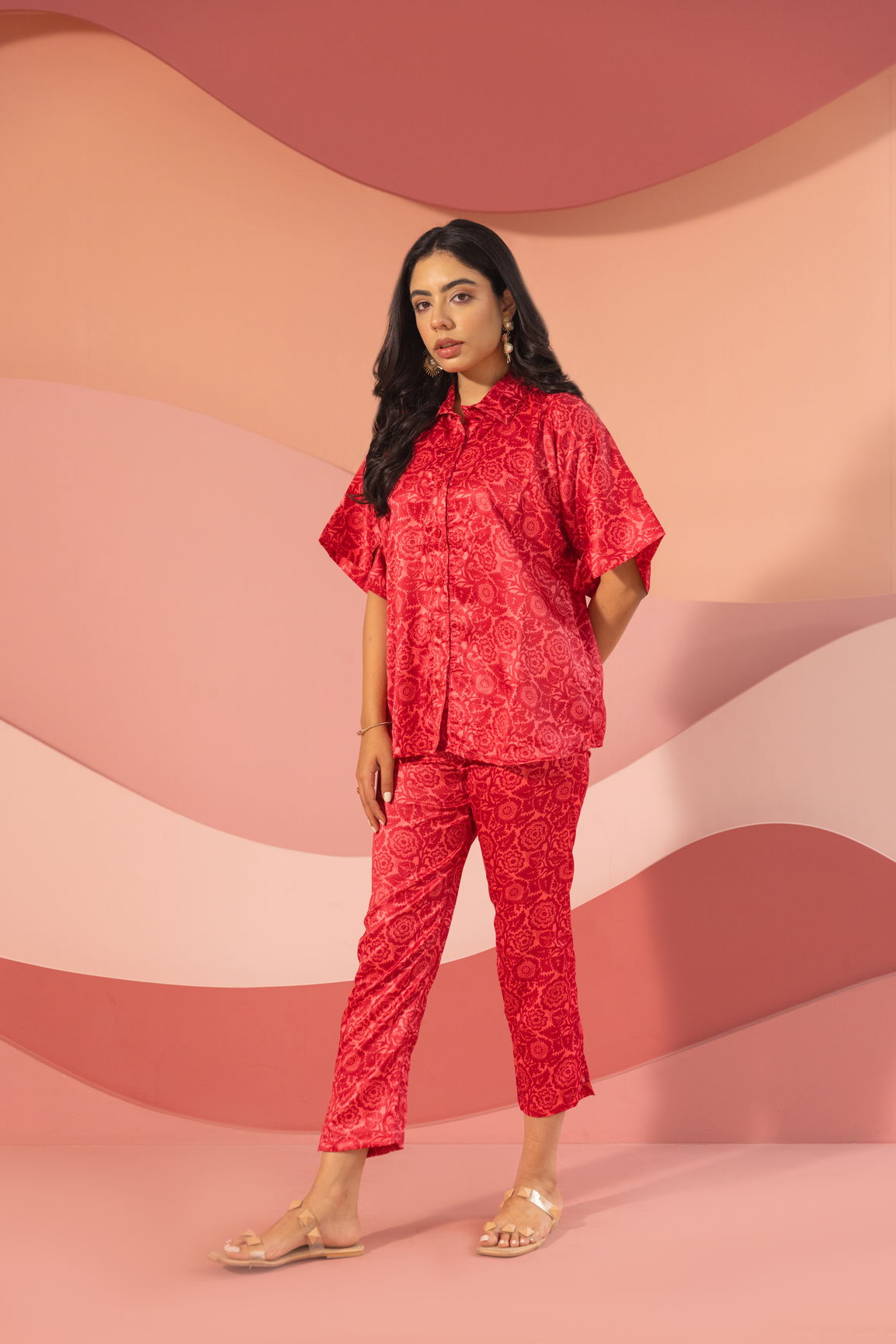 Stylish woman wearing pink satin co-ord set against a sleek background.