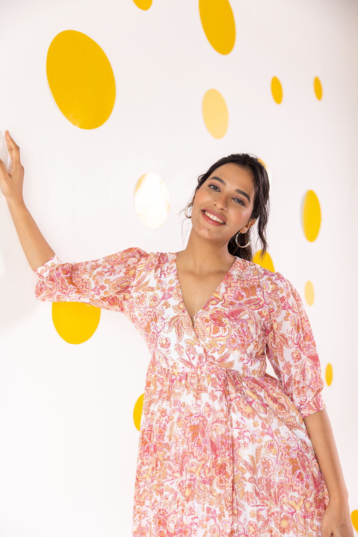 Woman wearing pleated motif maxi dress against a colorful backdrop.