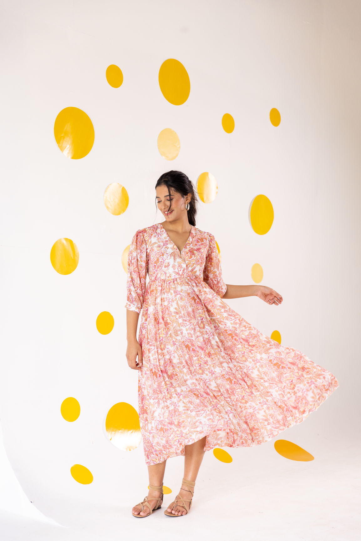 Woman wearing a floral pleated motif maxi dress against a bright background.