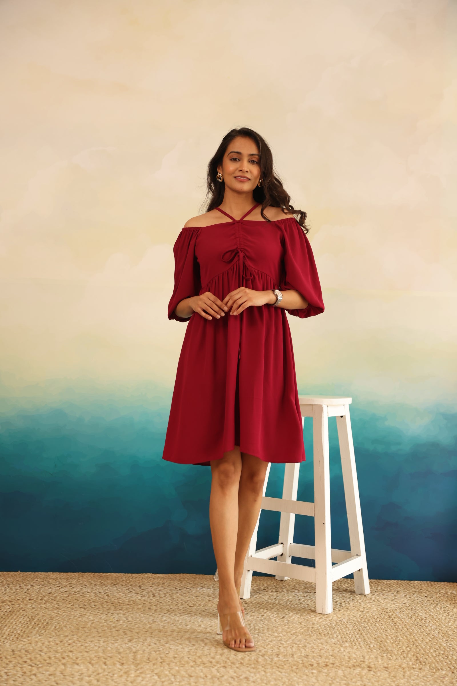 Burgundy midi dress on model against a soft gradient background.