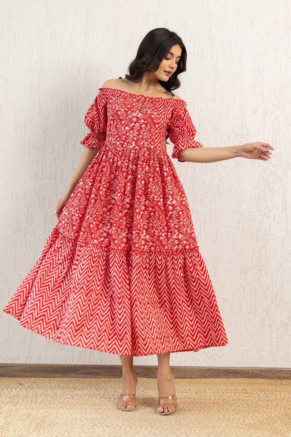 Red off-shoulder cotton maxi dress with floral design and tiered hem.