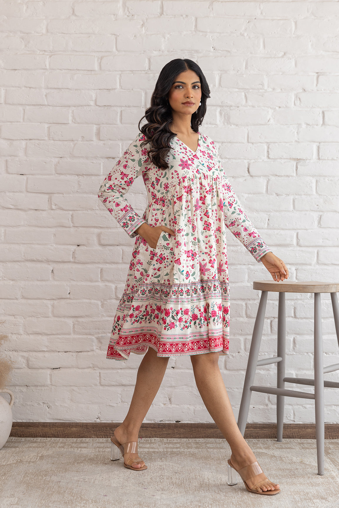 Floral cotton midi dress on a model against a white brick wall.