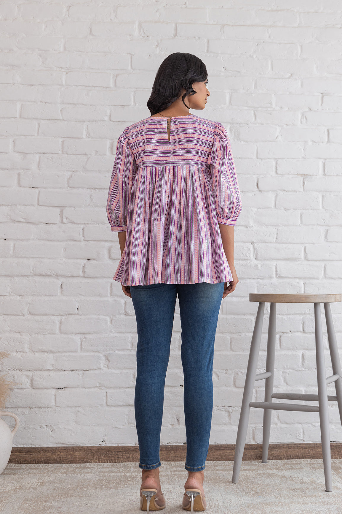 Back view of pink striped cotton top on model.