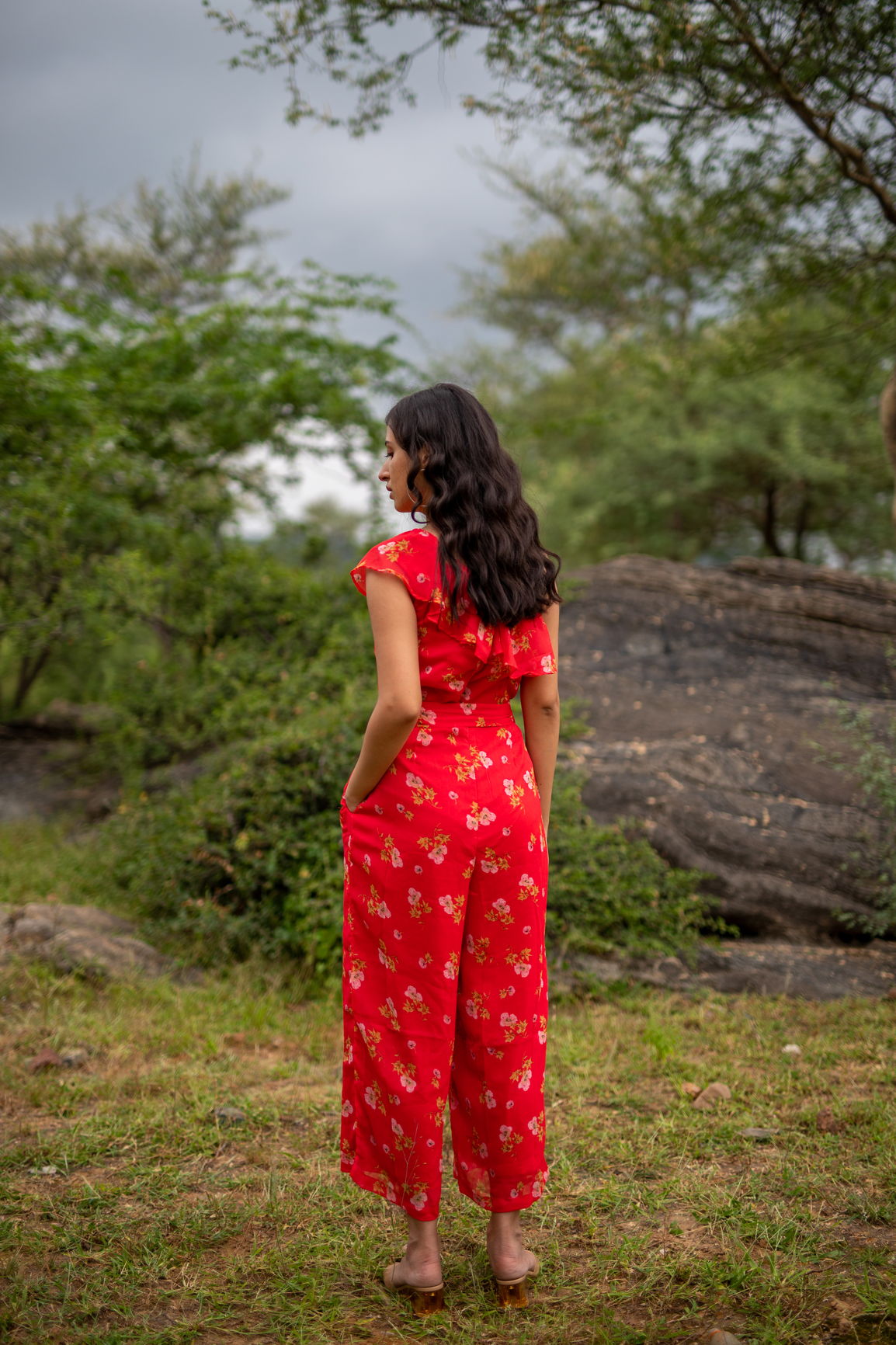 Floral one-shoulder jumpsuit in vibrant red with floral patterns.