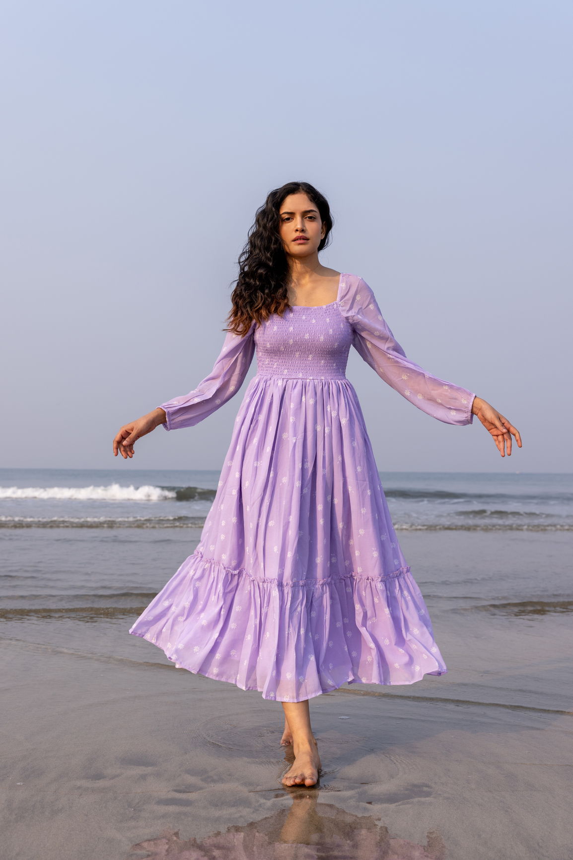 LILAC SMOCKED MAXI dress on model walking by the beach.