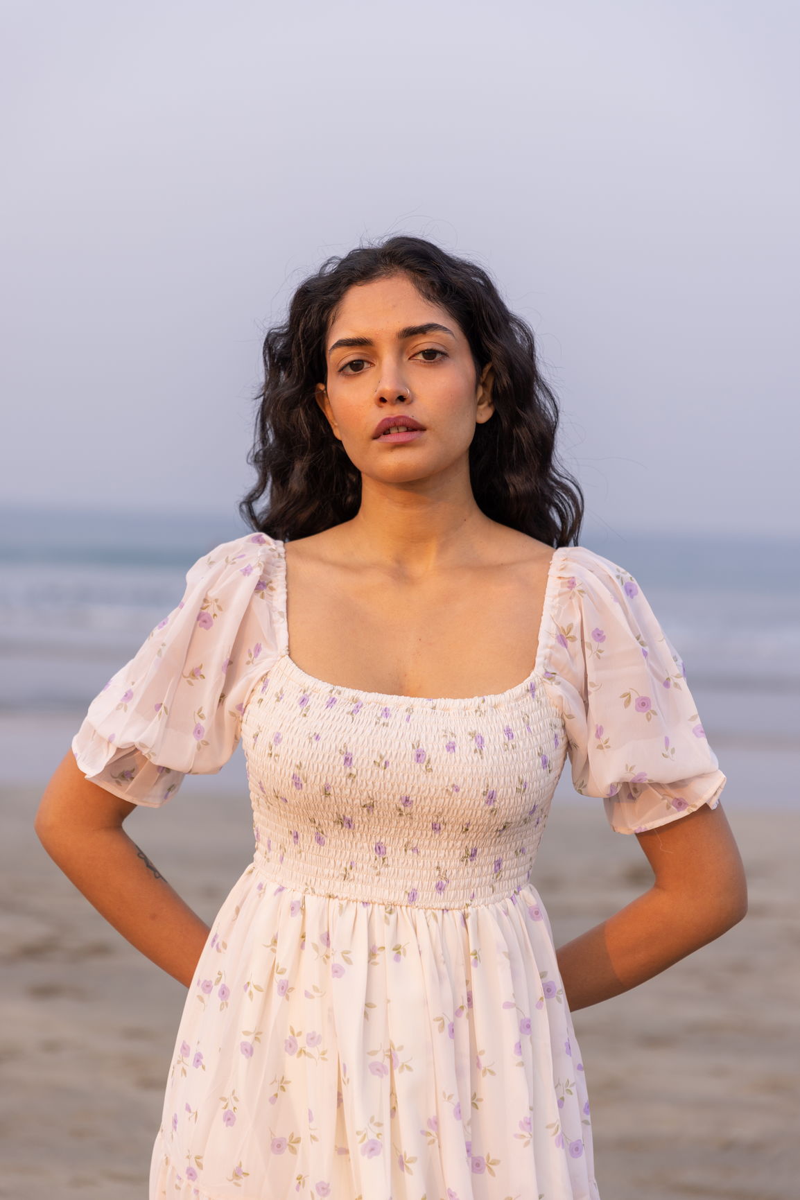 Model wearing MINIMAL MAXI floral dress on the beach at sunset.