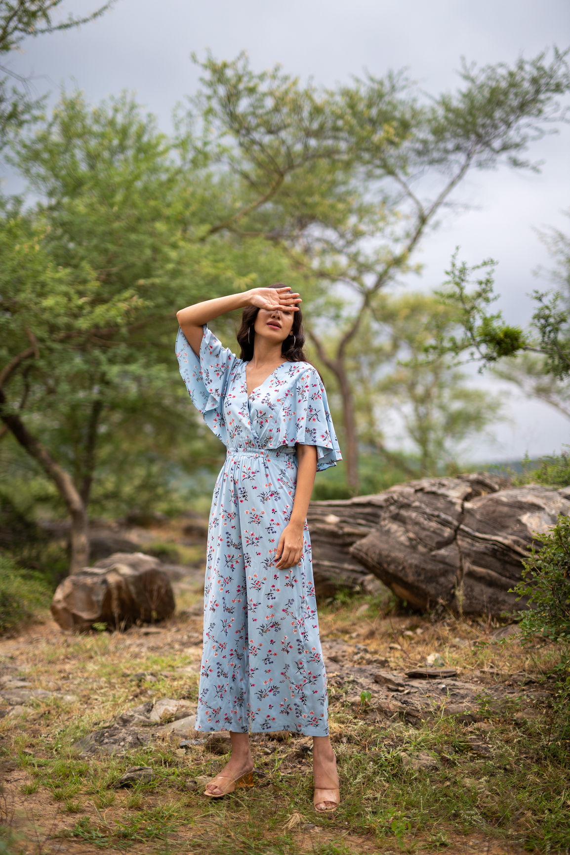 Sky blue floral jumpsuit styled in a natural outdoor setting.