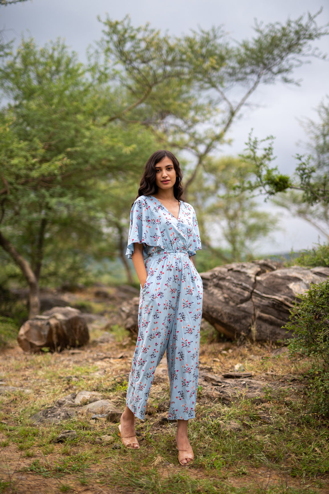 Sky blue floral jumpsuit worn by a model in nature.