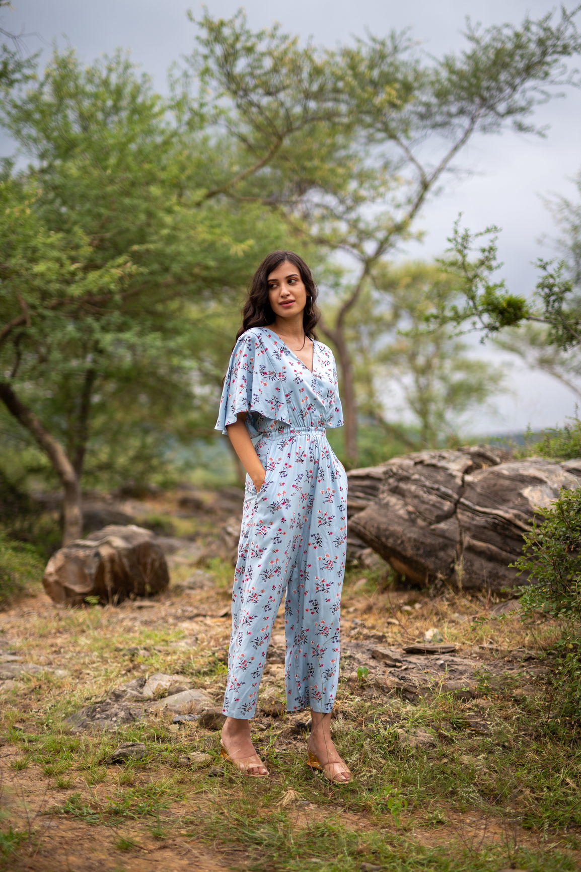 Sky blue floral jumpsuit modeled in a natural outdoor setting.