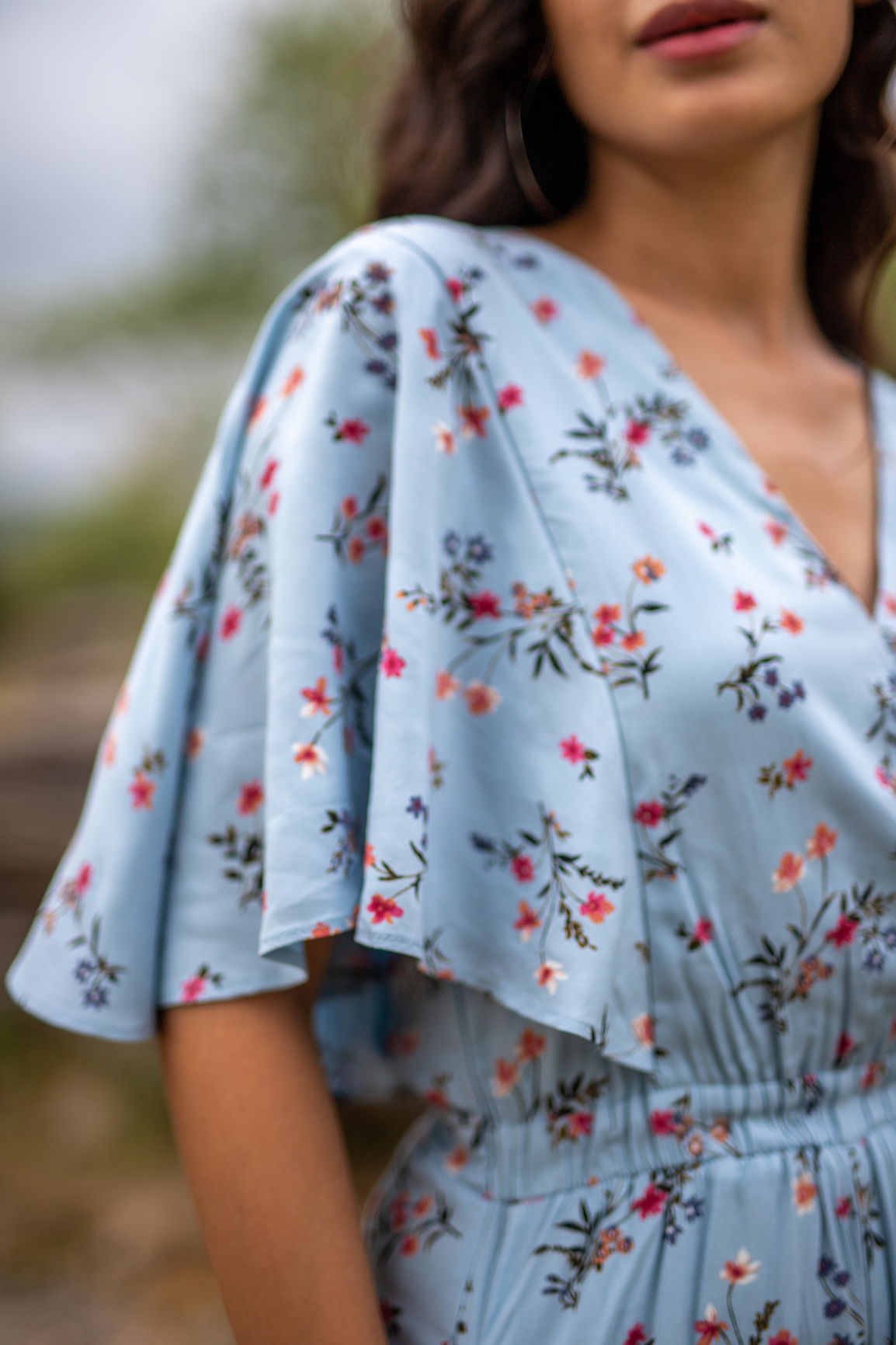 Sky blue floral jumpsuit with flutter sleeves and vibrant blooms.