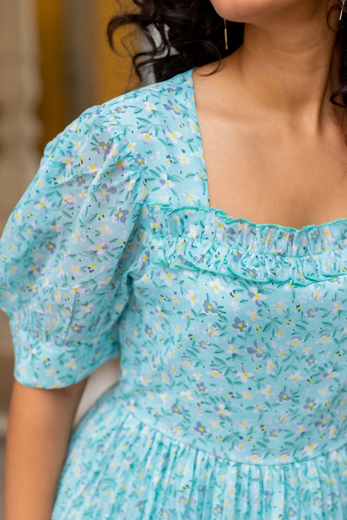 Sky blue pleated maxi dress with floral print and puffed sleeves.
