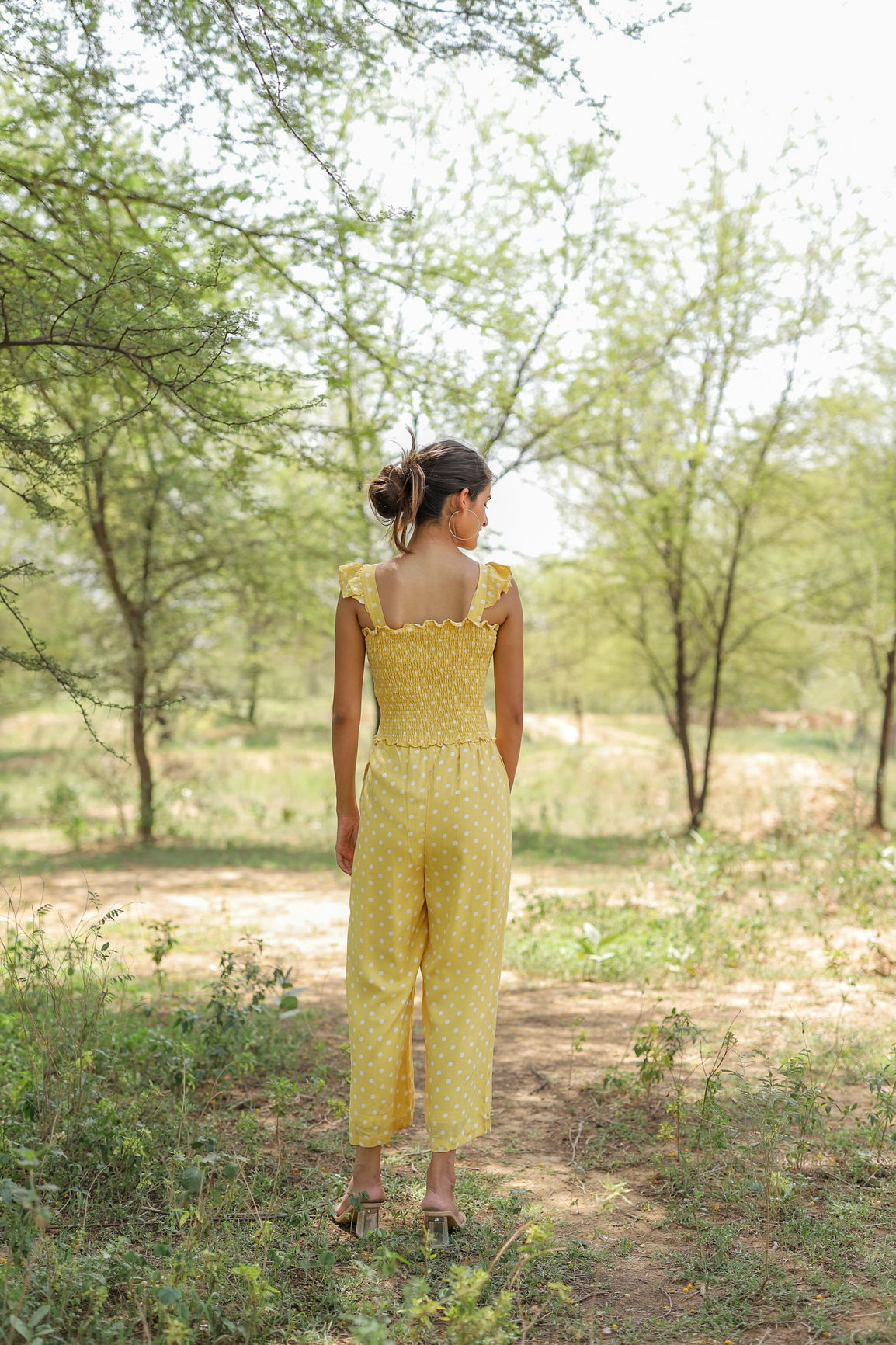 Yellow polka dot jumpsuit in a natural outdoor setting.