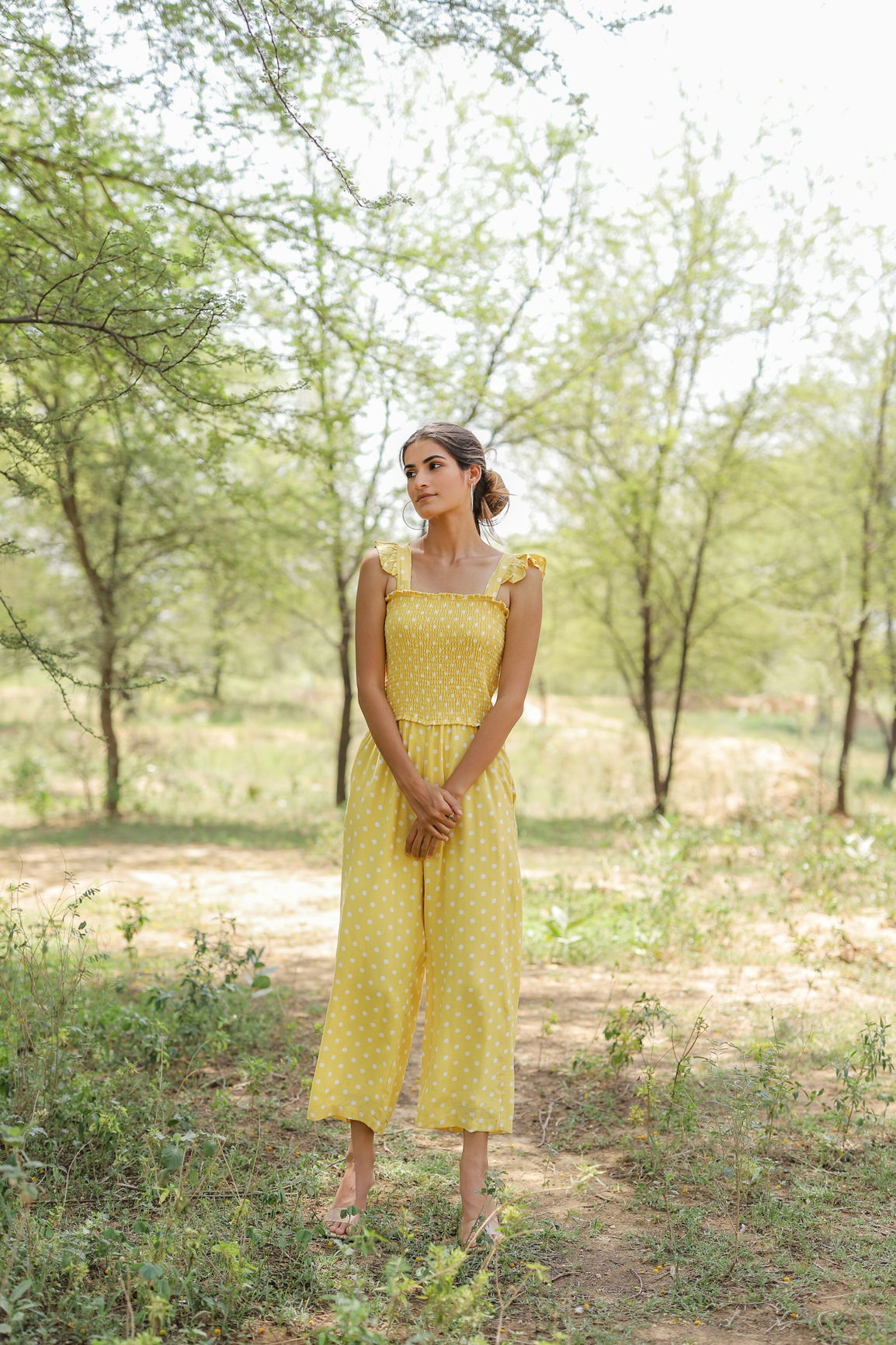 Yellow polka dot jumpsuit worn outdoors in natural setting.