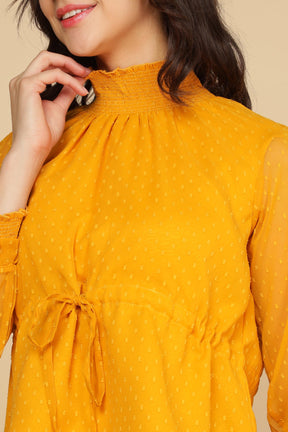 Elegant yellow chiffon top with smocked neckline and tie detail.