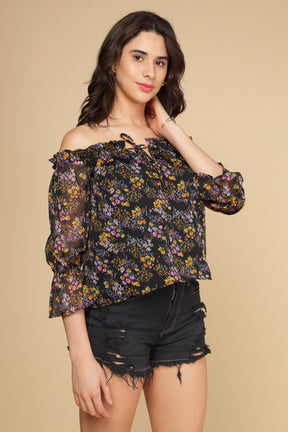 Multi floral off-shoulder top styled with distressed black shorts.