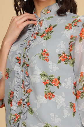 Pastel blue ruffle shirt top with floral design and detail.