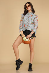 Pastel blue ruffle shirt top with floral design and stylish accessories.