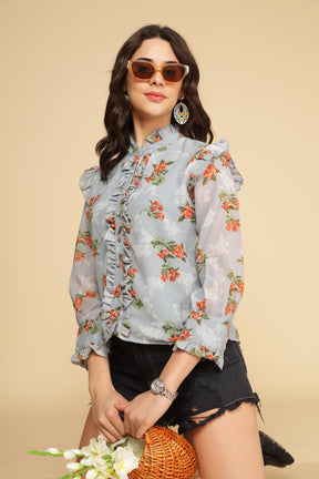 Pastel blue ruffle shirt top with floral design and stylish accessories.