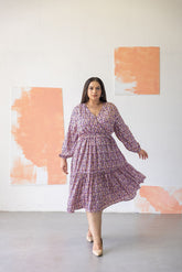 Elegant woman wearing ABSTRACT PRINT MAXI - POLAGO PLUS dress in studio setting.