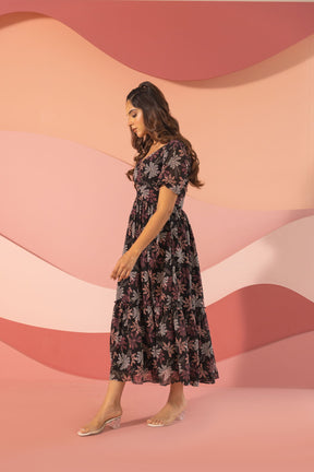 Black floral maxi dress on model against pastel background.