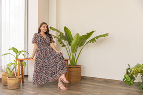 Model wearing black floral print nursing maxi dress indoors.