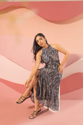 Black halter neck maxi dress displayed on a model against a colorful background.
