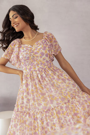 Model wearing MOSAIC PRINT MAXI dress with floral pattern and flutter sleeves.