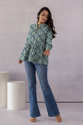 Woman wearing a green floral cotton top with blue jeans.