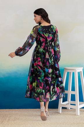Woman wearing black geometric print chiffon maxi dress, vibrant colors.