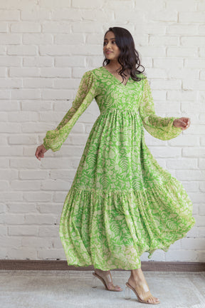 Green and yellow floral maxi dress with flowing sleeves and tiered hem.