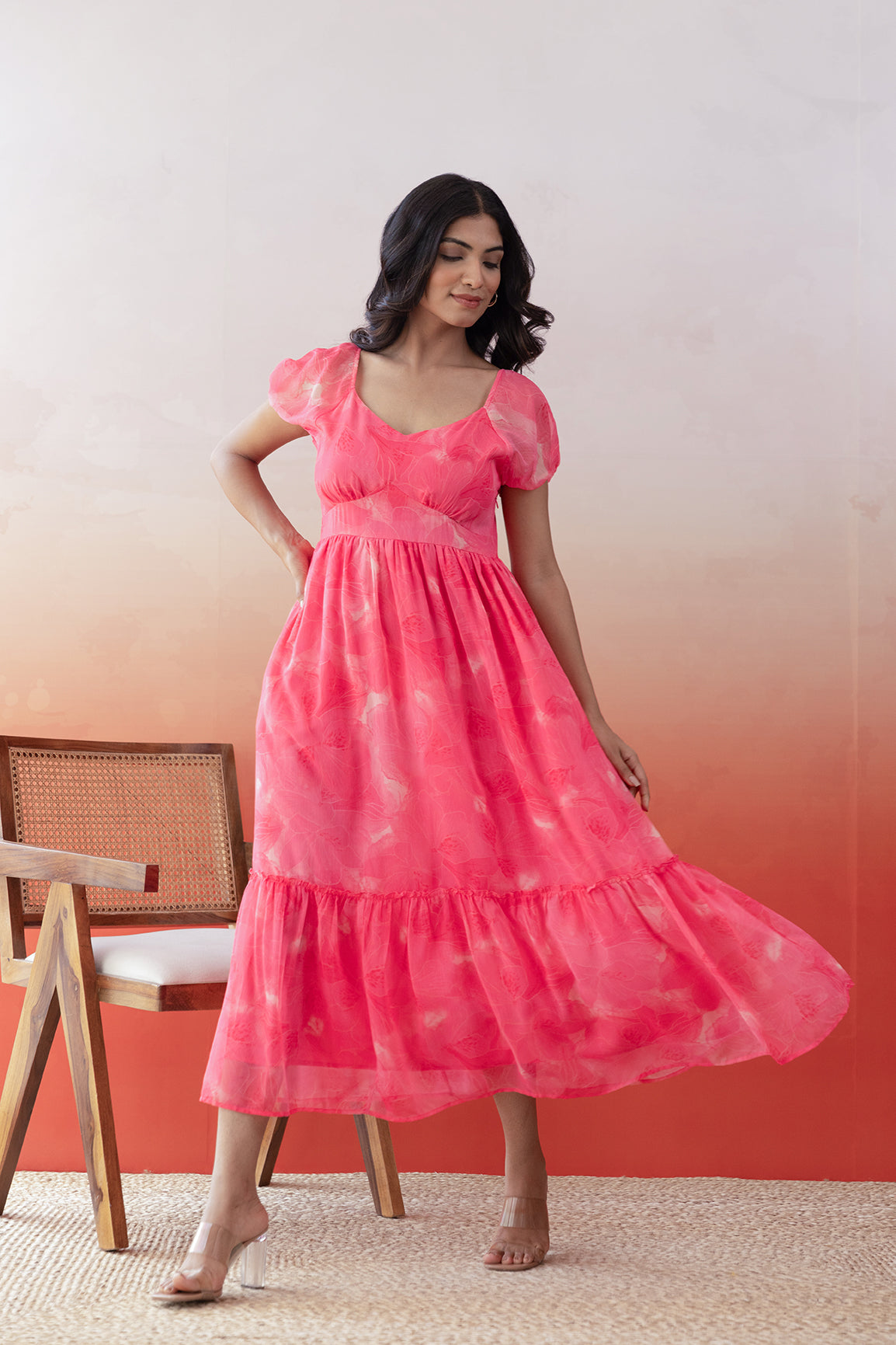 "Model wearing pink chiffon maxi dress in a stylish setting."