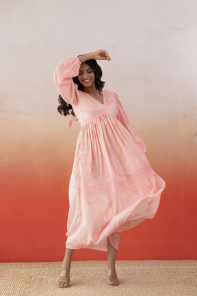 Woman in a pink marble-patterned maxi dress, smiling joyfully.