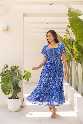Woman wearing electric blue tropical maxi dress in a sunny setting.