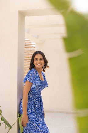 Smiling woman in an electric blue tropical maxi dress.
