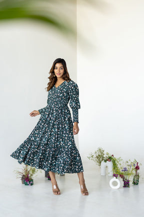 Emerald green floral smocked maxi dress on a model with plants.