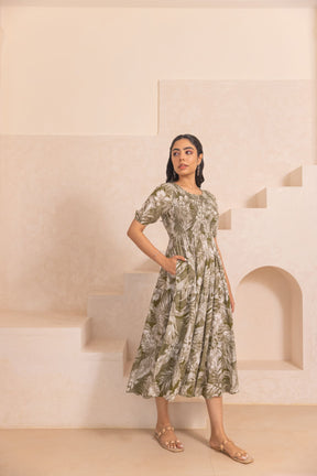 Green tropical smocked cotton maxi dress on model in neutral setting.