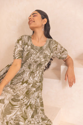 Green tropical smocked cotton maxi dress, model sitting elegantly.